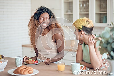 Laughing dark-skinned woman and girlfriend during breakfast Stock Photo