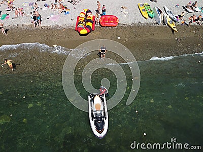 Happy people swim on air mattress behind a high speed water bike. Tourists ride on inflatable watercraft boat. Sea Editorial Stock Photo