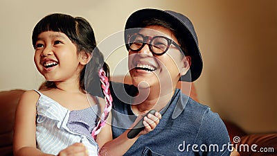 Happy Person, a Cute Girl Smiling sitting on Sofa with Her Parent. Happiness Moment by a Big Teeth Smile Stock Photo