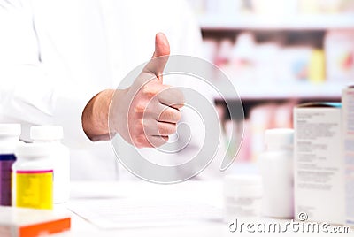Happy pharmacist showing thumbs up at pharmacy counter Stock Photo