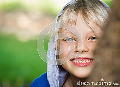 Happy playing child peeking from behind a tree Stock Photo