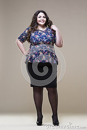 Happy plus size fashion model in casual clothes, fat woman on beige studio background, overweight female body Stock Photo