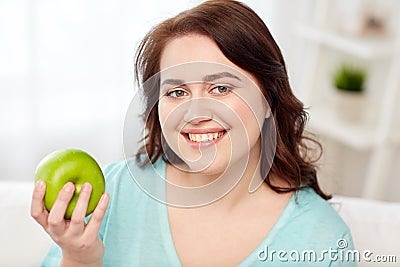 Happy plus size woman eating green apple at home Stock Photo