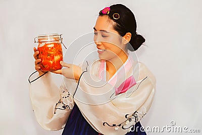 Beautiful Asian woman wearing a traditional Korean hanbok admires bottles of delicious and colorful pickled kimchi. Stock Photo