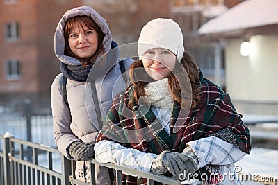 Happy positive two stylish girls standing on street in city. Closeup portrait funny joyful attractive young women dressing winter Stock Photo