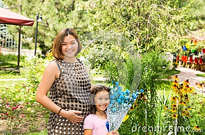 Happy pregnant asian mom and child girl hugging. The concept of childhood and family. Stock Photo