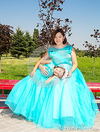 Happy pregnant asian mom and child girl hugging. The concept of childhood and family. Beautiful Mother and her baby outdoor Stock Photo