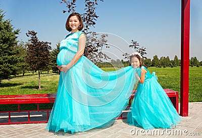 Happy pregnant asian mom and child girl hugging. The concept of childhood and family. Beautiful Mother and her baby outdoor Stock Photo