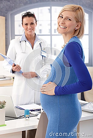 Happy pregnant businesswoman at doctor's office Stock Photo