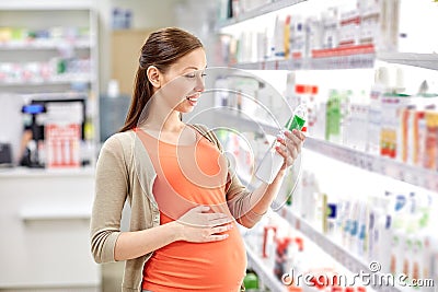 Happy pregnant woman choosing lotion at pharmacy Stock Photo