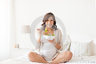 Happy pregnant woman eating salad at home Stock Photo