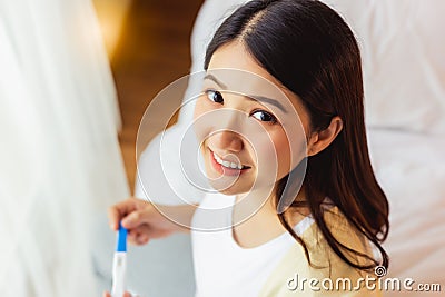 Happy pregnant woman holding pregnancy test and get happy because single mother has baby with smiley face. Young Mother waiting Stock Photo