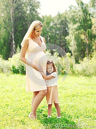 Happy pregnant woman, little child daughter hugging mother in summer Stock Photo