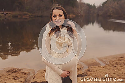 Happy pregnant woman in soft warm cozy outfit walking outdoors Stock Photo