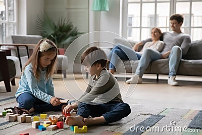 Happy preschool siblings enjoying playtime while parents resting. Stock Photo
