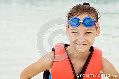 Happy preteen girl in life vest and swimming goggles against blu Stock Photo