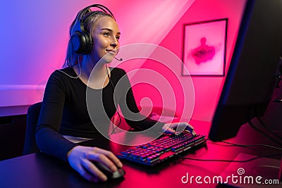 Happy Pretty Blonde Gamer Girl Playing Online Video Game on Her Personal Computer. Stock Photo