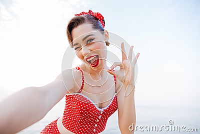 Happy pretty pinup girl in red swimsuit showing okay sign Stock Photo