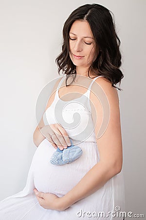 happy pretty woman enjoying pregnancy. mother to be is expecting parent. cute big tummy. pregnant brunette in light room Stock Photo