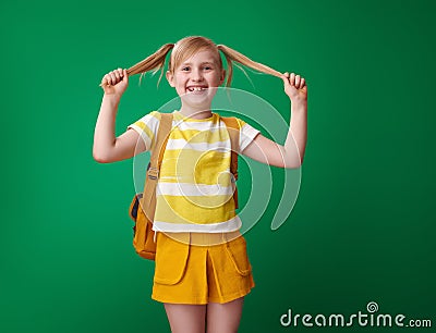Happy pupil with backpack with tails against green background Stock Photo