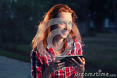 Happy redhair girl with digital tablet in hands posing outdoors, casual modern life Stock Photo