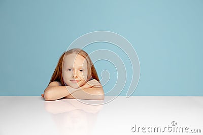 Happy redhair girl isolated on blue studio background. Looks happy, cheerful, sincere. Copyspace. Childhood, education Stock Photo