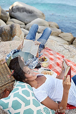 Happy and relaxed couple reading during a picnic on the rocks, n Stock Photo