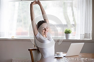 Happy relaxing woman stretching in front of computer at home Stock Photo