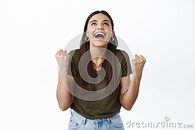 Happy and relieved young woman scream of joy and happiness, winning prize, triumphing, achieve goal or prize, raising Stock Photo