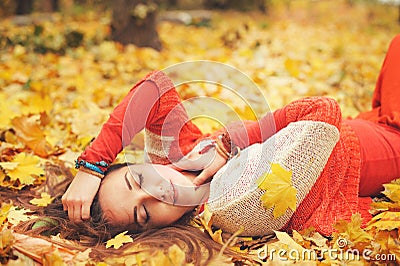 Happy resting girl portrait, lying in autumn maple leaves in park, closed eyes, dressed in fashion sweater Stock Photo