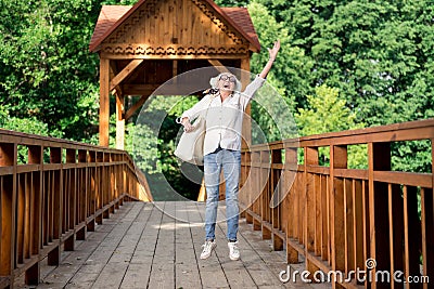 Happy retired woman jumping while enjoying nice eco tourism Stock Photo