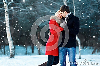 Happy romantic young couple walking in winter park on flying snowflakes snowy Stock Photo