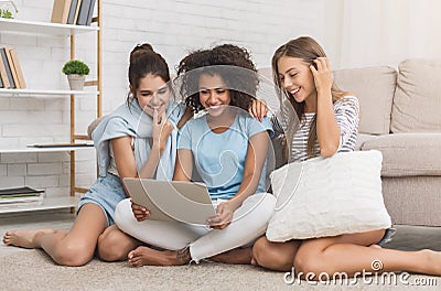 Happy roommates using laptop, surfing internet at home Stock Photo