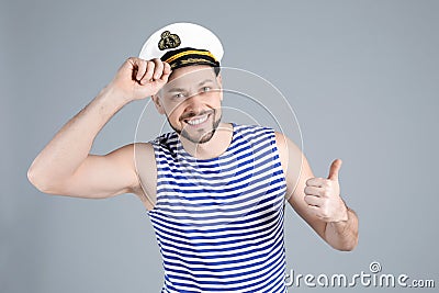 Happy sailor wearing cap on grey background Stock Photo