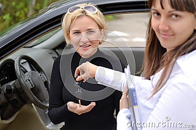 Happy saleswoman handing over car keys Stock Photo