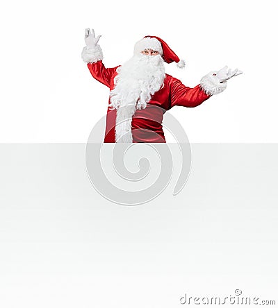 Happy Santa Claus jumping out from behind the blank banner Stock Photo