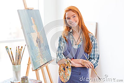 Happy satisfied woman painter finished painting picture in art studio Stock Photo