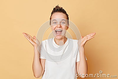 Happy satisfied woman wearing white T-shirt washes hair standing with shampoo foam on her head isolated over beige background Stock Photo