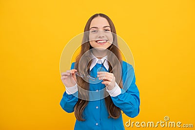 Happy school aged kid hold eyeglasses for vision correction yellow background, eyecare Stock Photo