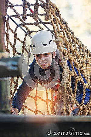 Happy school girl enjoying activity in a climbing adventure park Stock Photo