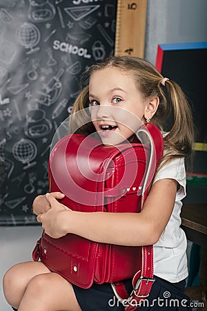 Happy schoolchild in the classroom with big backpack Stock Photo