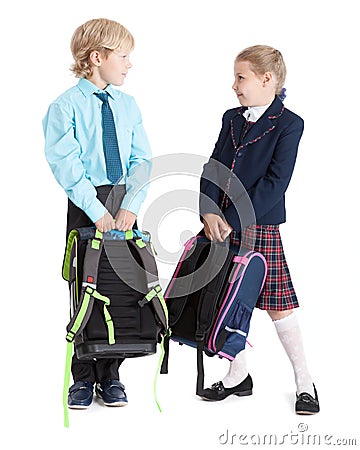 Happy schoolchildren in school uniform with schoolbags looking each other, full length, isolated white background Stock Photo