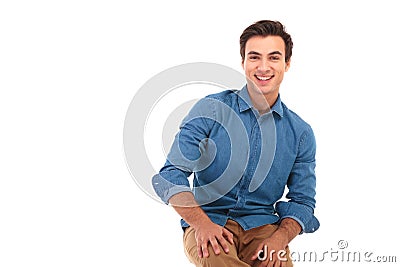 Happy seated young casual man with hands on knees Stock Photo