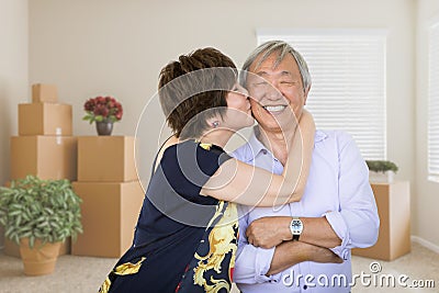 Happy Senior Chinese Couple Inside Empty Room with Moving Boxes Stock Photo