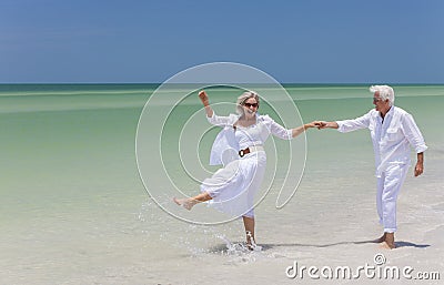 Happy Senior Couple Dancing Holding Hands on A Tropical Beach Stock Photo