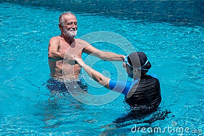 Happy Senior couple dancing In Swimming Pool Together. having fun .Swimming teacher . Holding hands, training , retirement, Stock Photo