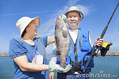 Happy senior couple fishing and showing big grouper Stock Photo