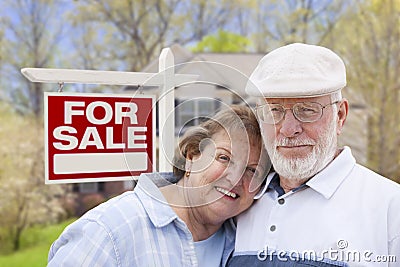Happy Senior Couple Front of For Sale Sign and House Stock Photo