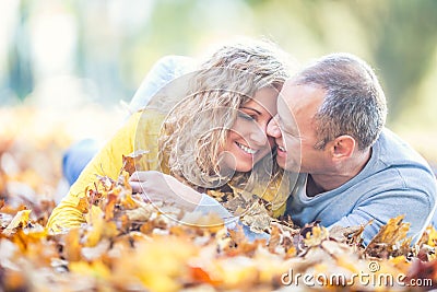 Happy mature 40s couple lying in autumn maple leaves Stock Photo