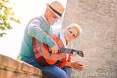 Happy senior couple playing a guitar and having a romantic date outdoor - Mature people having fun enjoying time together Stock Photo